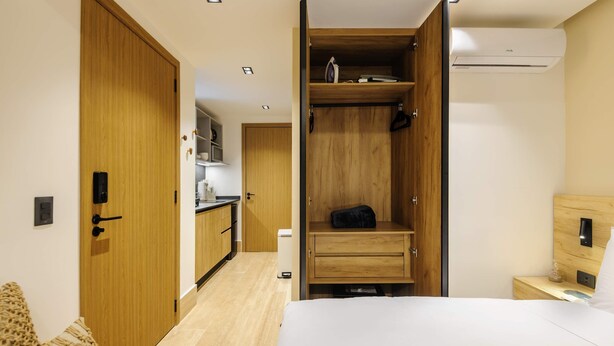 Una camera da letto con un letto, un armadio in legno, un comodino e una mensola a muro.