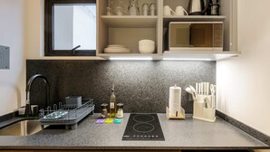 Una cucina con asciuga-stoviglie, bollitore, forno a microonde e un set di coltelli.