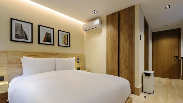 A hotel room with a large bed, a wooden headboard, a wall-mounted air conditioner, and framed pictures on the wall. - w Swish Loft W/balcony in Parque Mexico (Mexico City)