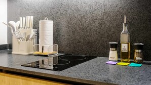 A kitchen counter with a black induction cooktop, a paper towel holder, a spice rack, and bottles of oil and salt. - w Swish Loft W/balcony in Parque Mexico (Mexico City)