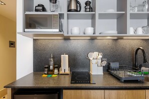 Una cocina moderna equipada con microondas, hervidor, cafetera y escurreplatos.