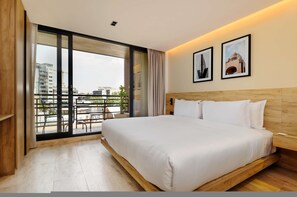 A modern hotel room with a large bed, a wooden headboard, a balcony with a view of buildings, and two framed pictures on the wall. - w Designer Loft W/balcony in Parque Mexico (Mexico City)