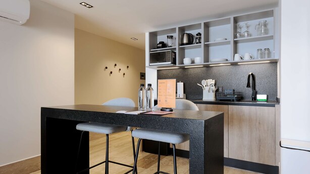 Una cocina moderna con barra, armarios de madera y una estantería empotrada.