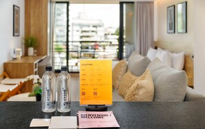 Mostrador de recepción de hotel con un cartel de bienvenida, dos botellas de agua y un libro de visitas.