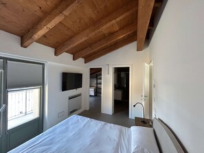 A bedroom with a bed, a TV, a window, and a door leading to a bathroom. - w Luxury 5BR Retreat Near Navigli (Milan)