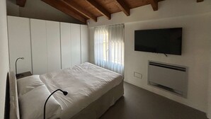 A bedroom with a bed, a television mounted on the wall, and a window with curtains. - w Luxury 5BR Retreat Near Navigli (Milan)