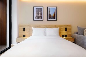 A hotel room with a wooden headboard, white bedding, two framed pictures on the wall, and a grey sofa. - w Engaging Loft w/ Balcony in Parque Mexico (Mexico City)