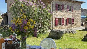 Un'area pranzo all'aperto con tavolo, sedie e un vaso di fiori.