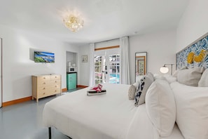 A hotel room with a bed, a dresser, a television, a painting, and a view of the outside. - Spirit of Sofia 12bd (Palm Springs)