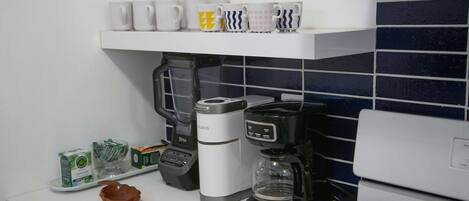 Una cocina con cafetera, hervidor y máquina de café sobre la encimera.