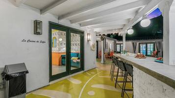 A kitchen area with a bar counter, a trash bin, and a dining area with chairs.