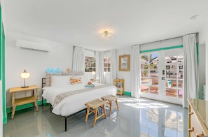 Een slaapkamer met een bed, nachtkastjes, een lamp, een spiegel en uitzicht door een glazen deur.
