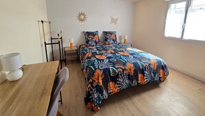 Un dormitorio con cama, escritorio, silla, ventana y lámpara en el techo.