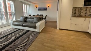 En moderne lejlighed med sofa, spisebord, stole og et køkken.
