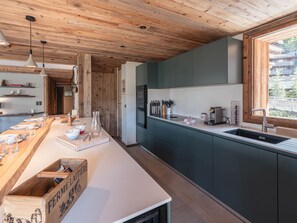 Eine moderne Küche mit Holzbalkendecke, einem großen Fenster und einem eingebauten Backofen.