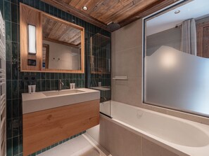 Ein modernes Badezimmer mit einem Holzwaschtisch, einem großen Spiegel, einer Badewanne und einer Duschkabine.