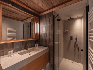 A modern bathroom with a wooden ceiling, a large mirror, a shower with a handheld showerhead, and a vanity with two sinks. - Ski-in/ski-out apartment, sunny view - 11 guests (Les Allues)