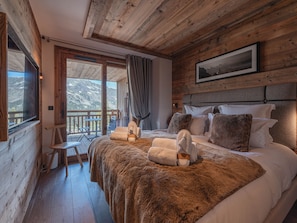 A wooden cabin bedroom with a bed, pillows, a window, and a balcony. - Ski-in/ski-out apartment, sunny view - 11 guests (Les Allues)