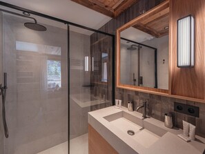 A modern bathroom with a glass shower enclosure, a large mirror, and a vanity with a sink and toiletries. - Ski-in/ski-out apartment, sunny view - 11 guests (Les Allues)