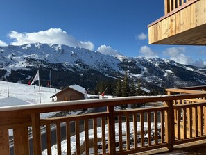A wooden balcony overlooking a snowy mountain landscape with a clear sky. - Ski-in/ski-out apartment, sunny view - 11 guests (Les Allues)