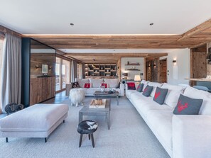 Un salon moderne comprenant un canapé, un pouf, une table basse et une cheminée.
