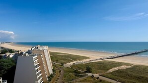 Vista costera con playa, muelle y edificios en primer plano.