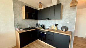 Una cocina moderna con gabinetes oscuros, una encimera de madera y un horno empotrado.