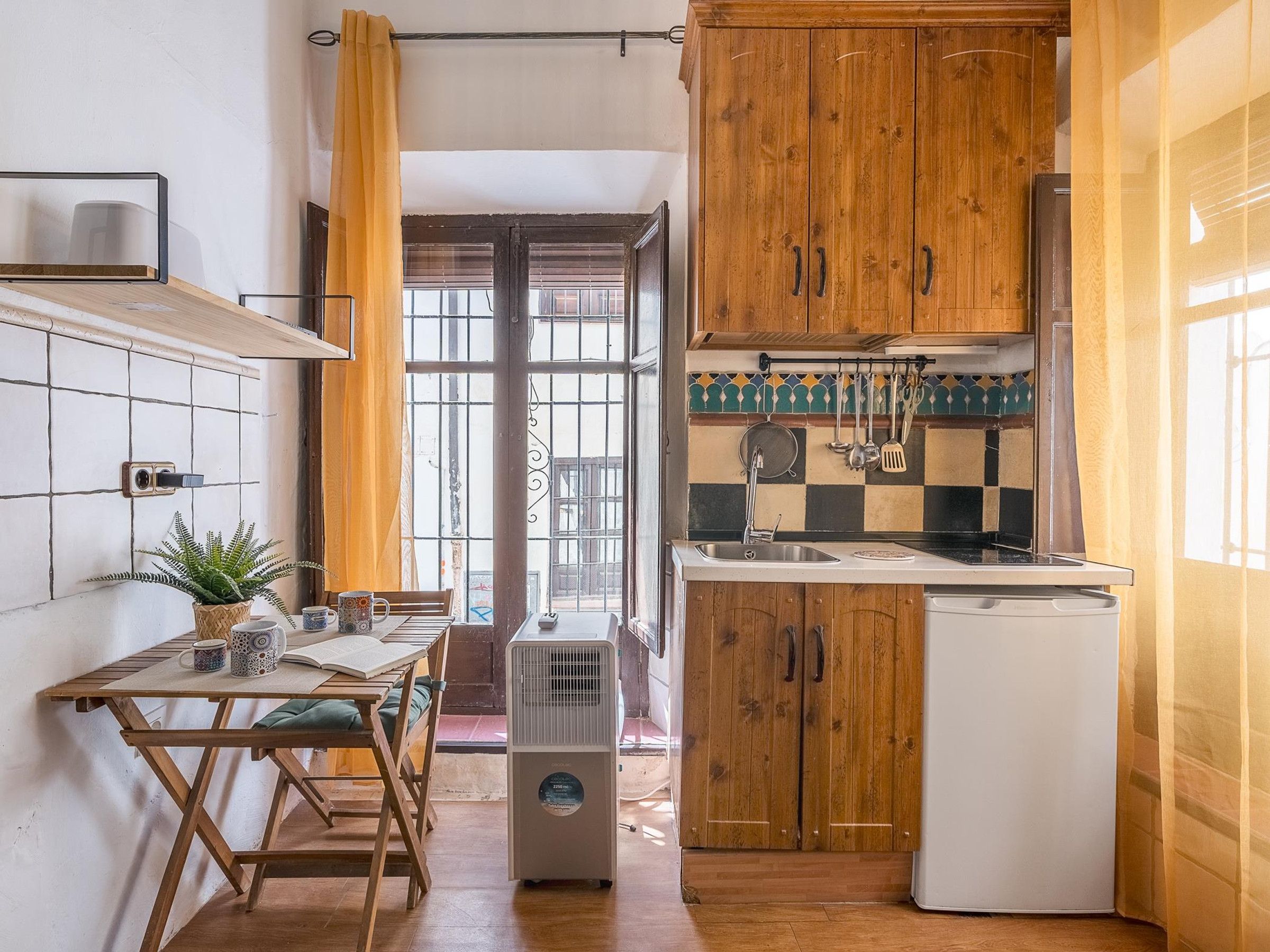 A compact kitchen with wooden cabinets, a white refrigerator, and a dining area with a table and chairs.
