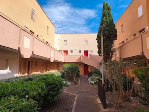 Ein Innenhof mit einem zentralen Weg, umgeben von Gebäuden mit Balkonen und Fenstern.