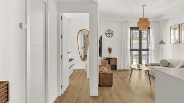 Una sala de estar moderna con un sofá, una mesa de centro, un televisor y un ventanal con cortinas.