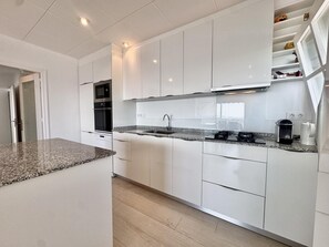 Eine moderne Küche mit weißen Schränken, einer Granitabdeckung und eingebauten Geräten.