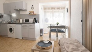 Un espacio habitable compacto con kitchenette, comedor y zona de estar acogedora.