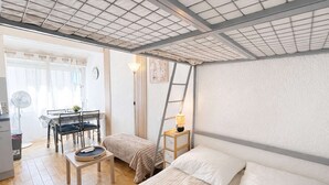 Una habitación pequeña con cama, una mesita, una silla, un escritorio y una escalera.