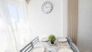 Un comedor con una mesa preparada para cuatro, un reloj de pared y una ventana con cortinas.