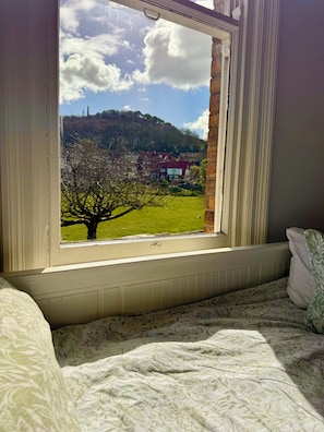 Ein Zimmer mit Fensterblick auf eine grüne Landschaft und ein rotes Haus.