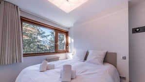 Un dormitorio con una cama grande, una ventana con cortinas, un radiador y un tragaluz.