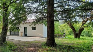 Ein Haus, umgeben von Bäumen, mit einem Schotterweg und einer Bank im Hintergrund.