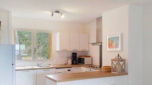 A modern kitchen with white cabinets, a wooden countertop, a coffee maker, a toaster, and a lantern. - Cross-apartment with terrace - 6 guests (Bormes-les-Mimosas)