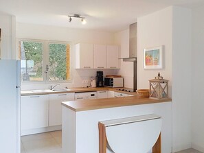 Eine moderne Küche mit weißen Schränken, einer Holzausziehtafel, einer Kaffeemaschine, einem Toaster und einer Laterne.