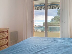 Ein Schlafzimmer mit Bett, Schminktisch und einem Balkon mit Blick.
