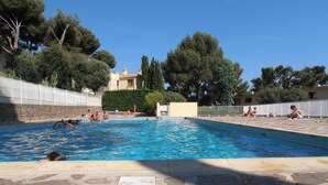 A swimming pool with stone tiles, surrounded by trees and a white fence. - Cross-apartment with terrace - 6 guests (Bormes-les-Mimosas)