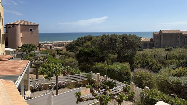 A coastal view with buildings, a beach, and a garden. - Apartment with sea view, parking - 4 guests (Fleury-Saint-Pierre-la-Mer)