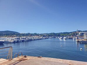 Ein Yachthafen mit vertäuten Booten, bewölkter Himmel und hügeliger Landschaft im Hintergrund.