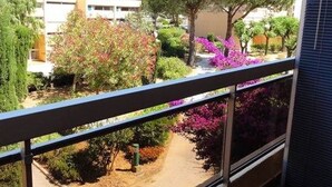 Un balcone con vista su un giardino, un albero e un edificio sullo sfondo.