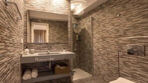 A modern bathroom with a stone-patterned wall, a glass shower enclosure, and a white toilet. - Room Boutique 32 (Dénia)