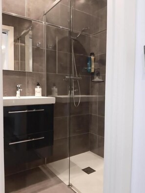 A modern bathroom with a glass-enclosed shower, a dark vanity, and a mirror above the sink. - Room Boutique 32 (Dénia)
