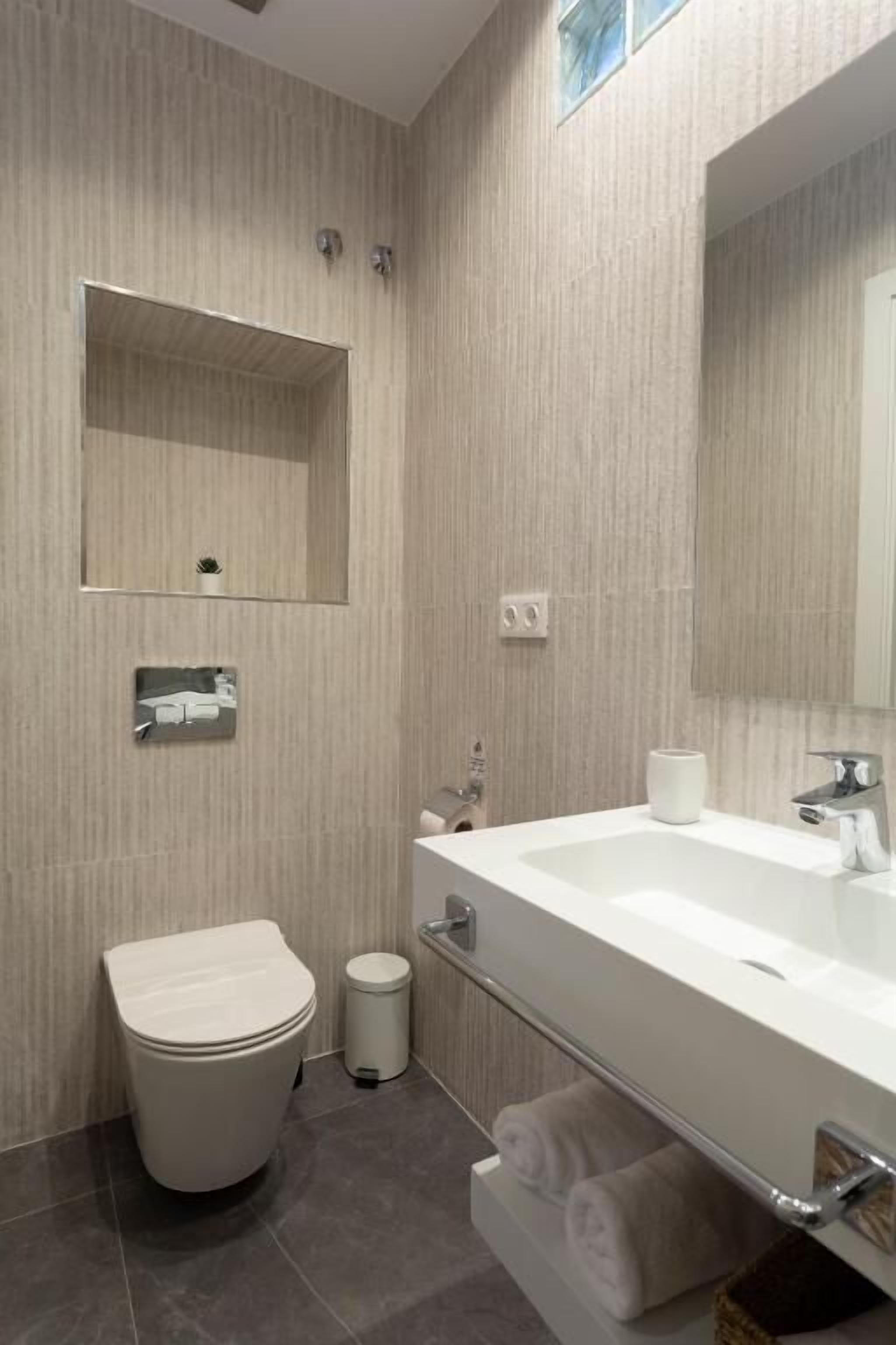 Un baño moderno con inodoro, lavabo y espejo.