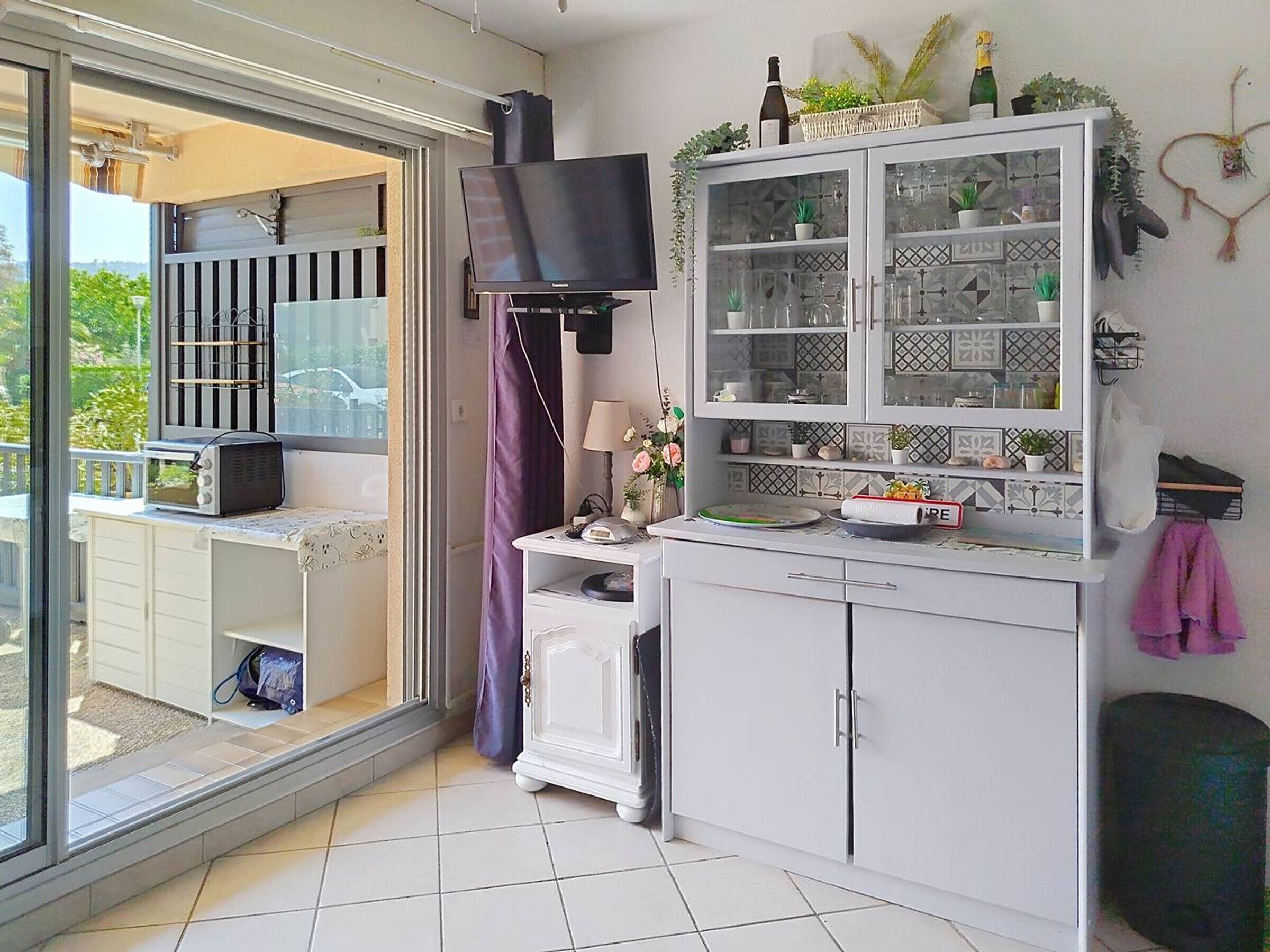 Eine Küche mit Fernseher, Schränken und einem Balkon.