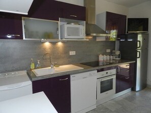 A modern kitchen with a built-in microwave, stainless steel appliances, and a dishwasher. - Cozy apartment, terrace, 4 guests (Le Lavandou)