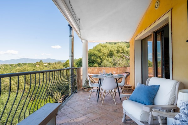 Un balcon avec une table et des chaises, un canapé et une vue sur la campagne.